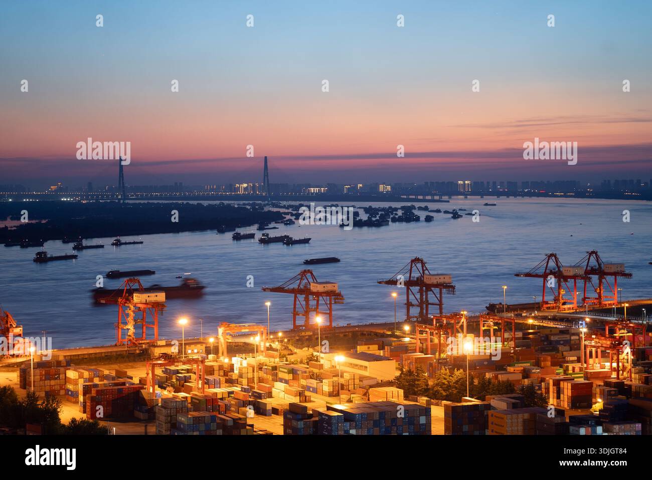 Les grues portuaires soulèvent la cargaison au crépuscule à Xinzhou Wuhan, en Chine. Banque D'Images