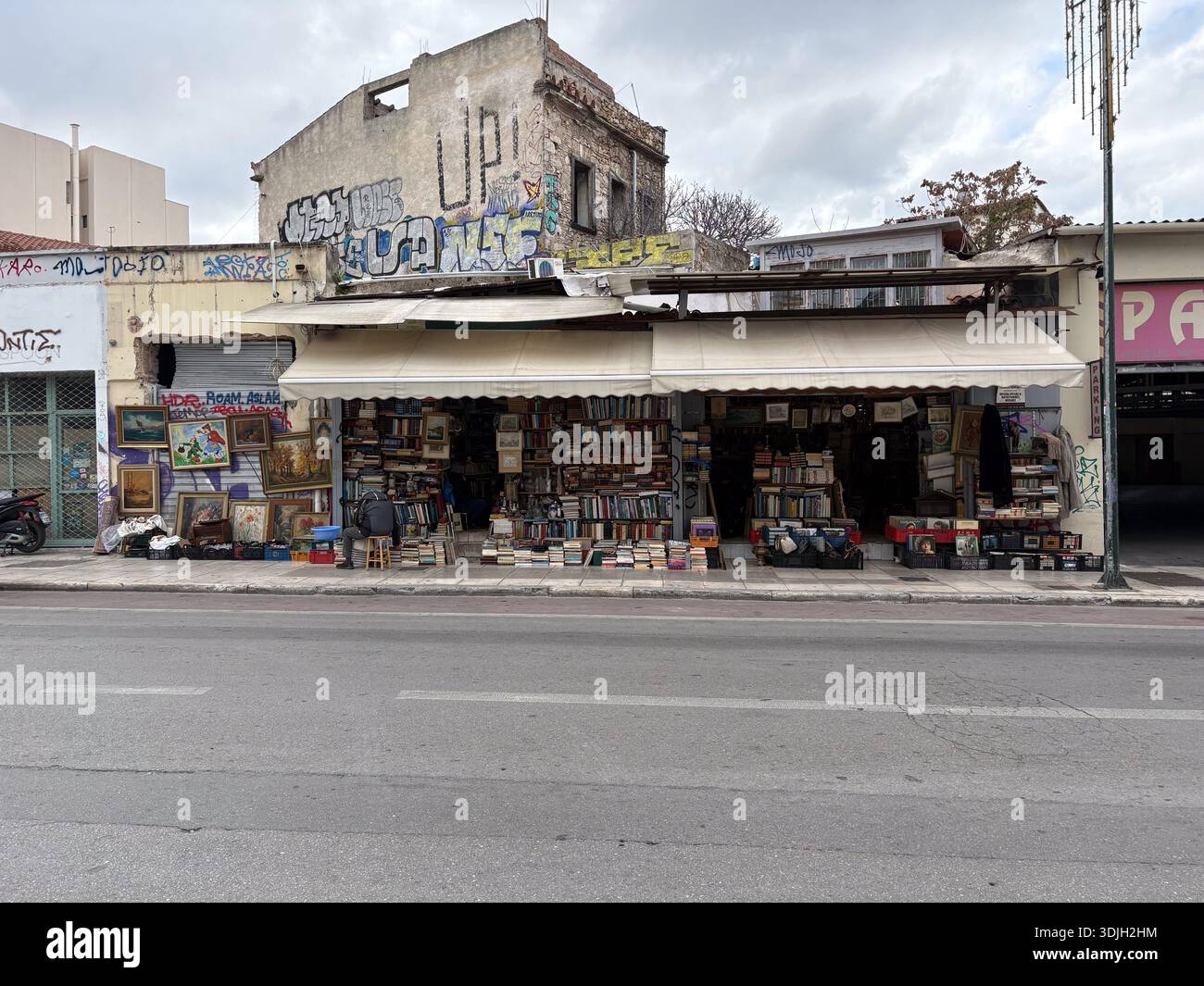 Le marchand de livres et d'art utilisé stalle dans une rue de la ville à Athènes, Grèce. La vue extérieure montre la façade de l'ancien bâtiment, l'art de rue et les graffitis lourds. Banque D'Images