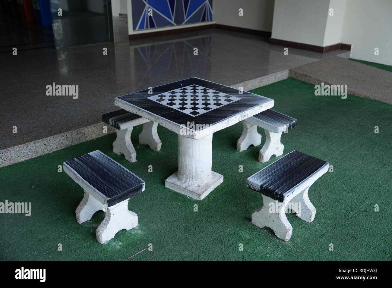 Table d'échecs en béton avec bancs environnants placés dans un espace de loisirs commun intérieur-extérieur. Banque D'Images