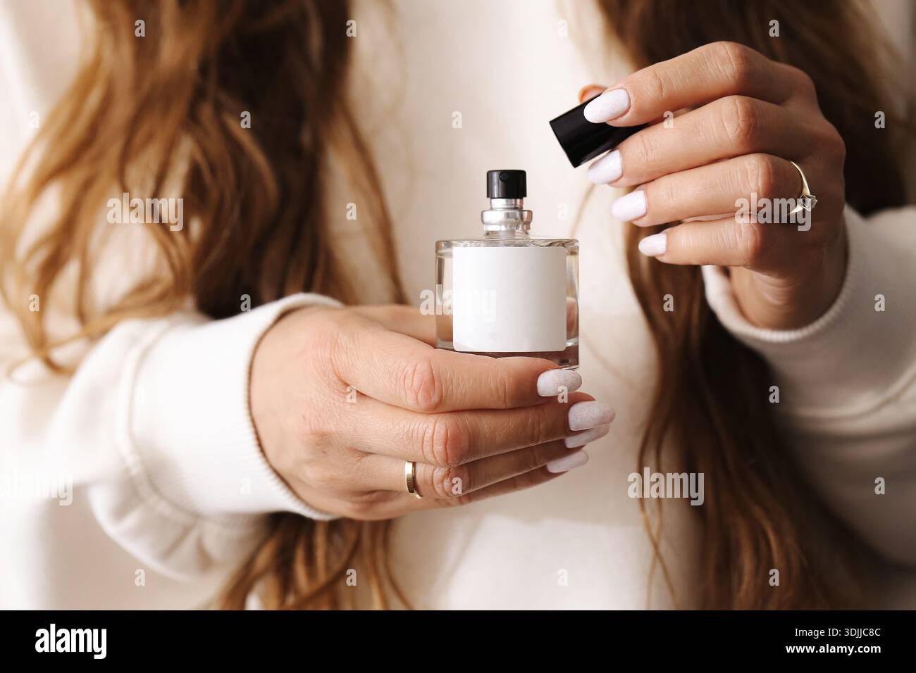 Ouverture bouteille de parfum dans les mains féminines gros plan. Préparation pour application de parfum. Concept de routine de soins personnels et de beauté. Banque D'Images