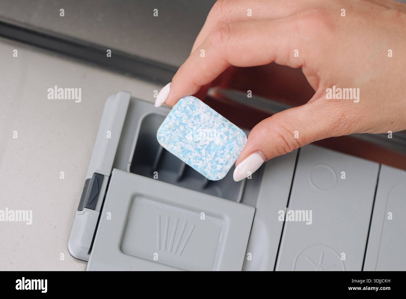 Pastille de détergent pour lave-vaisselle placée dans le distributeur. Préparation pour lave-vaisselle ménager gros plan. Routine de nettoyage de la cuisine. Entretien d'appareils ménagers. Banque D'Images