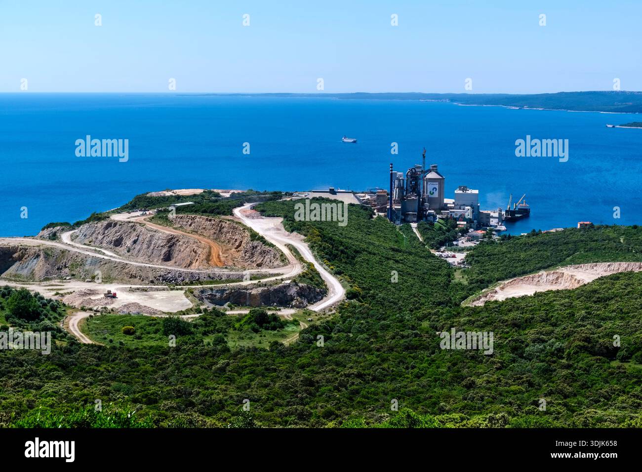 Vue sur une carrière de calcaire et une cimenterie sur la côte de Koromačno. La mer Adriatique et les collines boisées sont visibles au loin. Banque D'Images