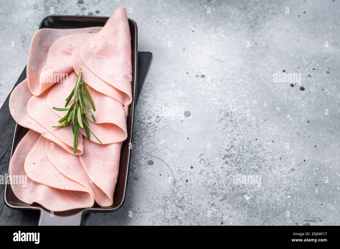 Jambon tranché gourmand sur une planche rustique, vous invitant à explorer de délicieuses recettes et de délicieuses associations. fond gris. vue de dessus. Banque D'Images