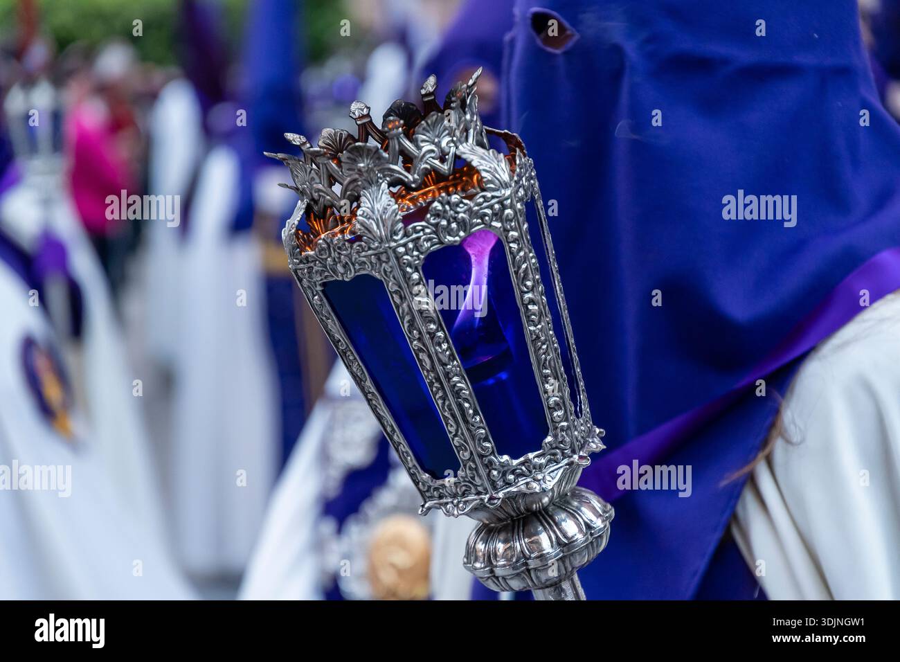 Les participants vêtus de tenues traditionnelles tiennent des bougies ornées tout en marchant dans une célébration culturelle vibrante. Banque D'Images