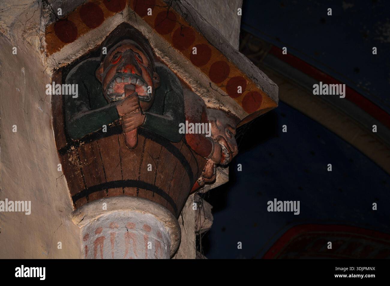 Langue calmée et visage non rempli : l’homme médiéval saisit une longue langue pendante de la bouche dentée pour s’arrêter de mentir, tandis que son compagnon utilise deux mains pour couvrir sa bouche : menteur et glouton sculptés sur la capitale médiévale peinte aux XIIe et XIIIe siècles l’église Saint-André ou l’église paroissiale Saint-André à Sauveterre-de-Béarn, Pyrénées-Atlantiques, Nouvelle-Aquitaine, Sud-Ouest de la France. Banque D'Images