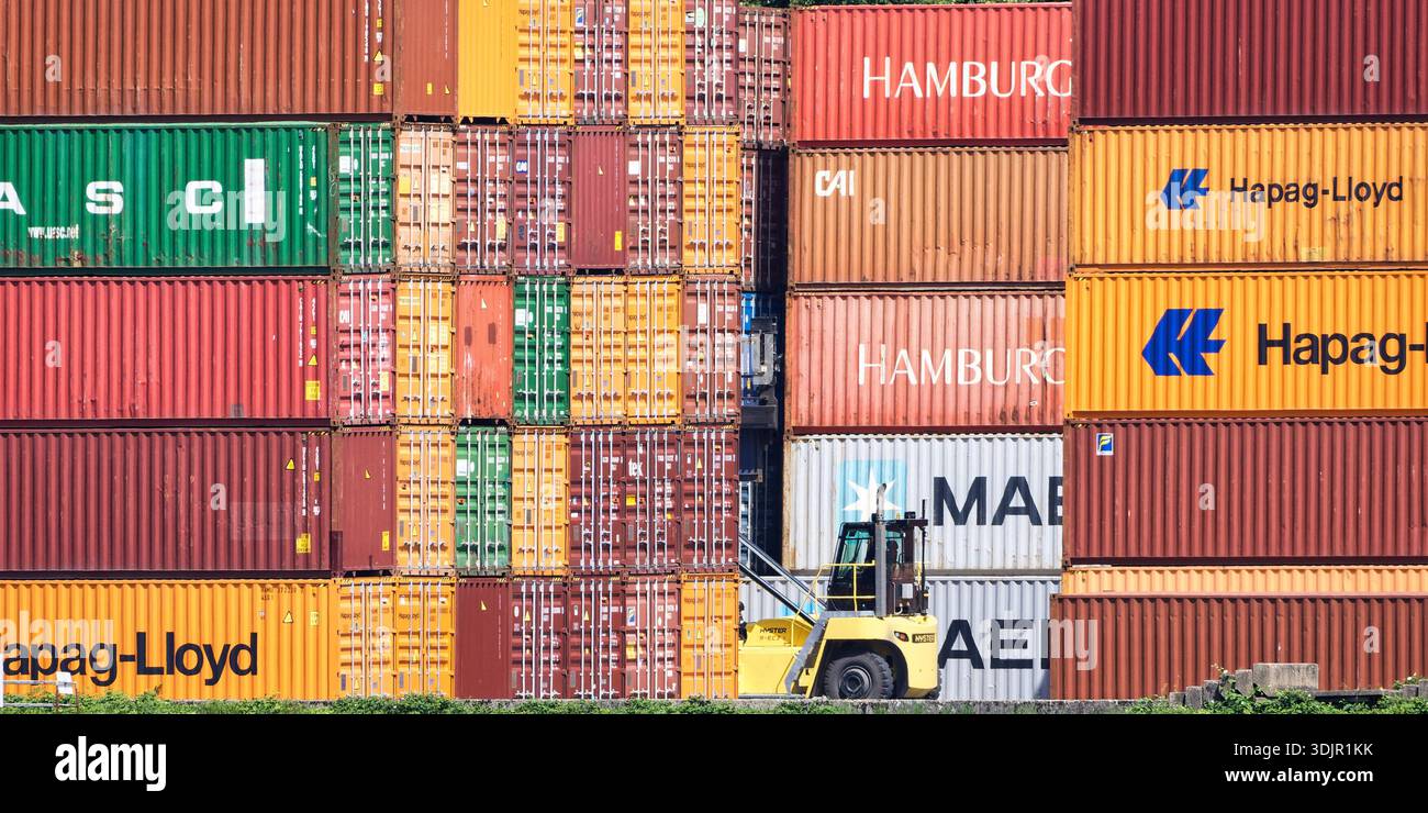 Cologne, Allemagne 23 juillet 2025 : gerbeur jaune à portée opérant entre des conteneurs de transport colorés au port de Niehl, Cologne. Logistique professionnelle a Banque D'Images