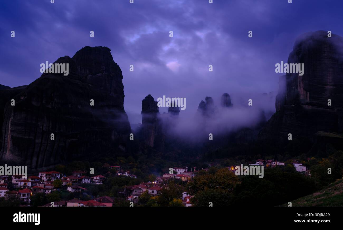 Le village de Kastraki sous les imposantes formations rocheuses des Météores, entouré de nuages spectaculaires et de brume nocturne, Thessalie, Grèce Banque D'Images