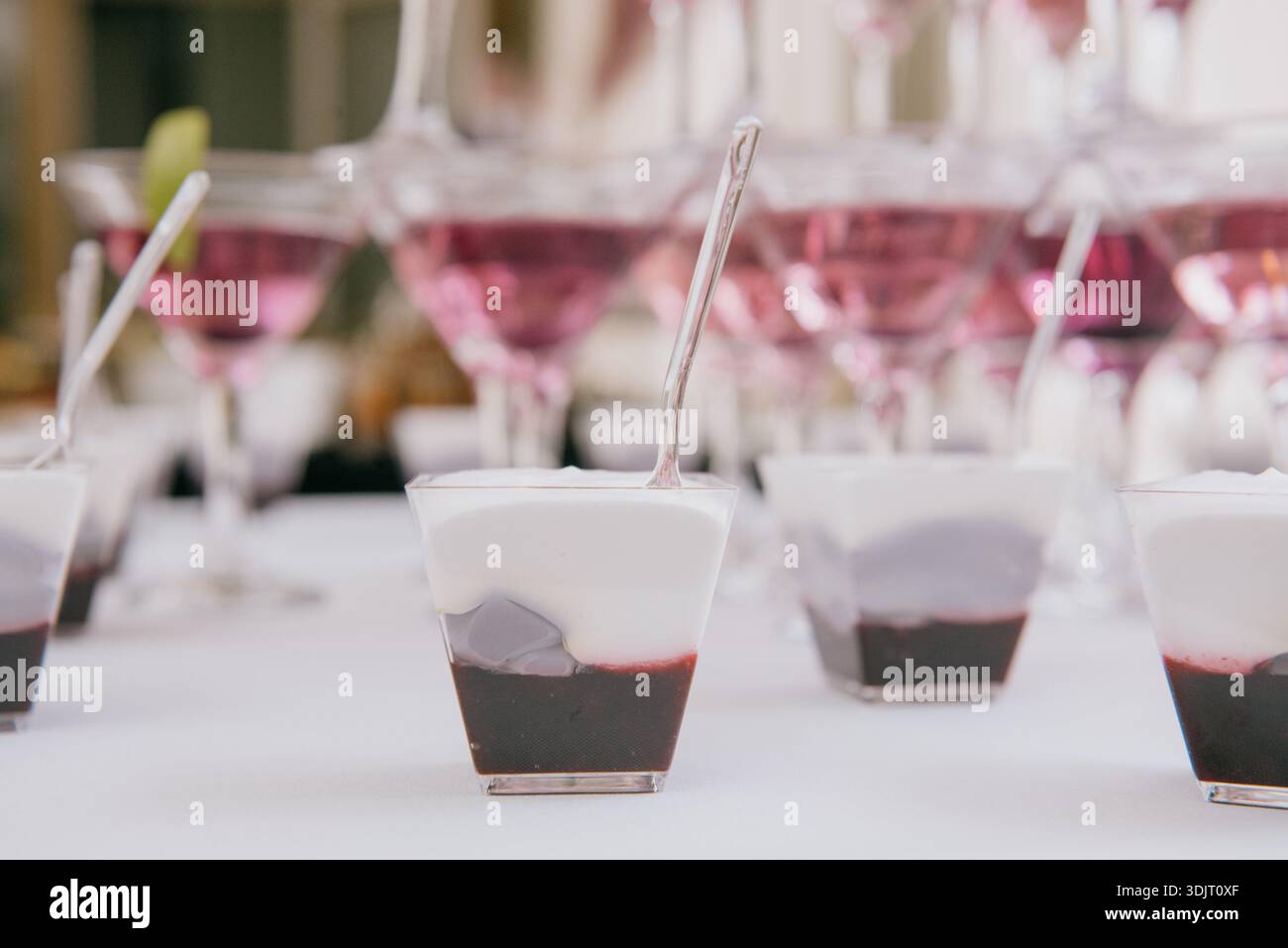 Desserts aux myrtilles en couches dans des tasses transparentes avec cuillères en plastique. Bonbons en mousse en portions avec baies noires et crème blanche pour les vacanciers Banque D'Images
