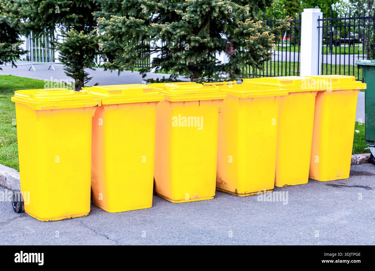 Une rangée de nouveaux conteneurs de déchets jaunes dans la rue de la ville. Poubelles modernes sur un trottoir Banque D'Images