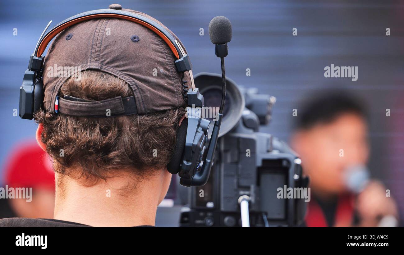 Cameraman portant un casque avec un microphone actionnant une caméra vidéo pendant un événement. Banque D'Images
