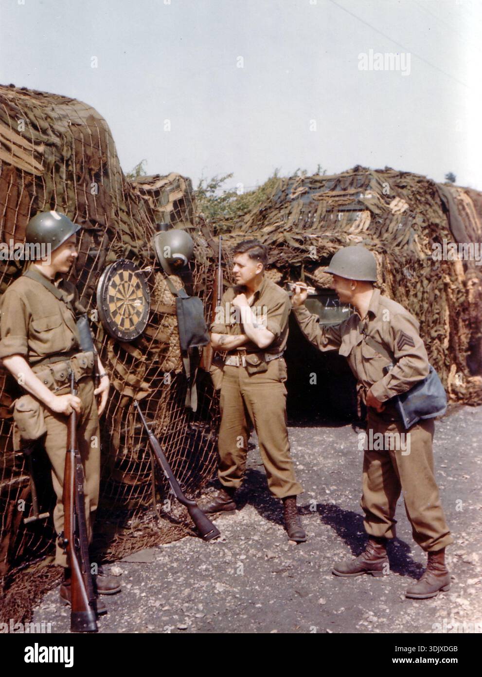 Trois jeunes soldats jouant aux fléchettes en attendant l'embarquement pour la Normandie. Le 6 juin 1944, une énorme force d'invasion Alllied impliquant 7000 navires et 140 000 hommes débarque avec succès sur les côtes françaises et établit cinq têtes de plage. Une campagne de tromperie réussie signifiait qu'une grande partie de la résistance allemande était à Calais et que les pertes étaient relativement peu nombreuses compte tenu de l'ampleur et des dangers de l'opération. Banque D'Images