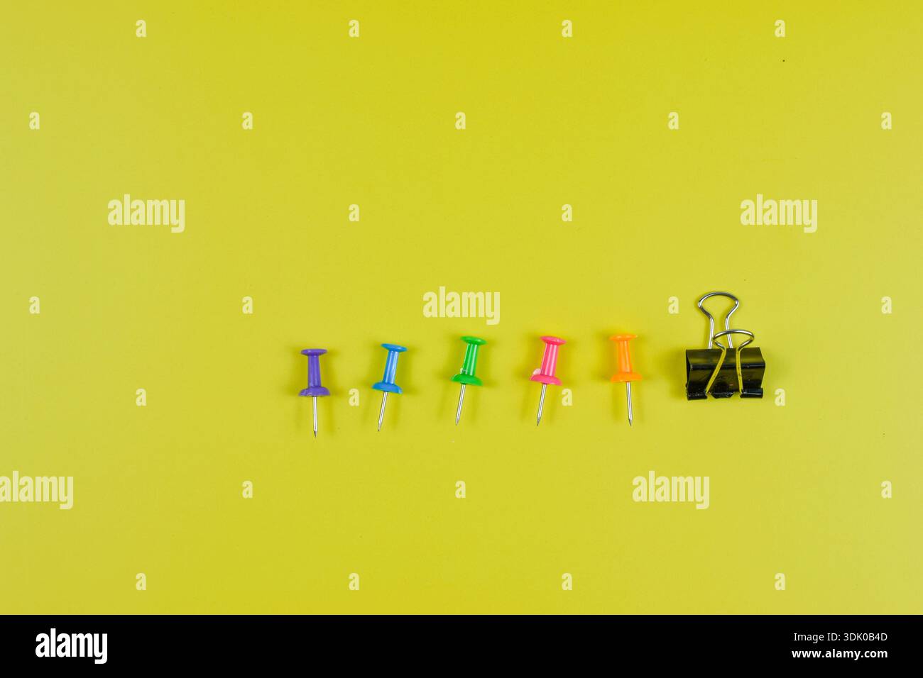 Les punaises colorées sur la surface jaune-vert soulignent l'organisation, la planification et le contraste visuel dans les environnements de bureau ou éducatifs. Banque D'Images