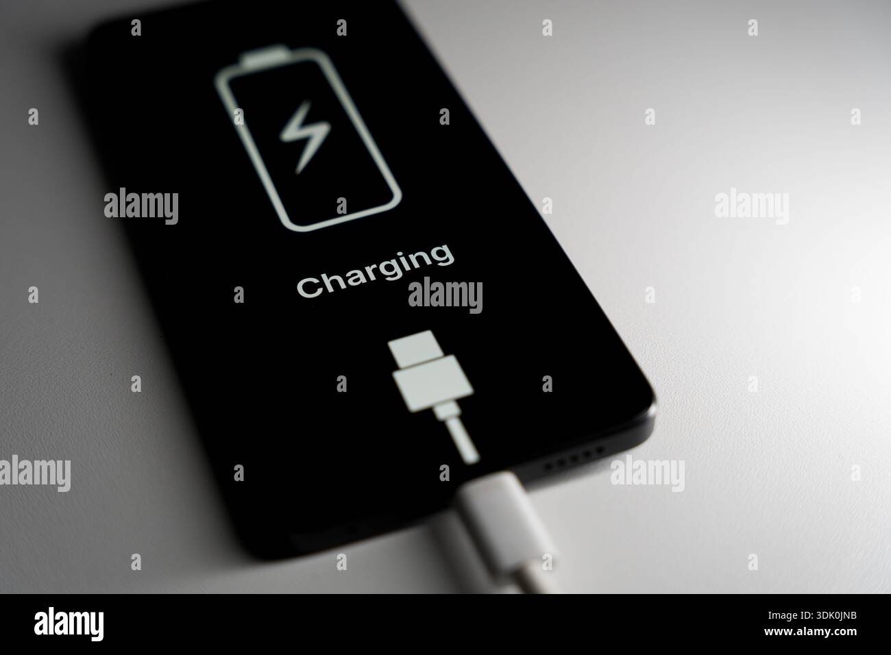 L'écran du smartphone affiche une icône de chargement de la batterie et le mot chargement sur fond noir. Photo de haute qualité Banque D'Images
