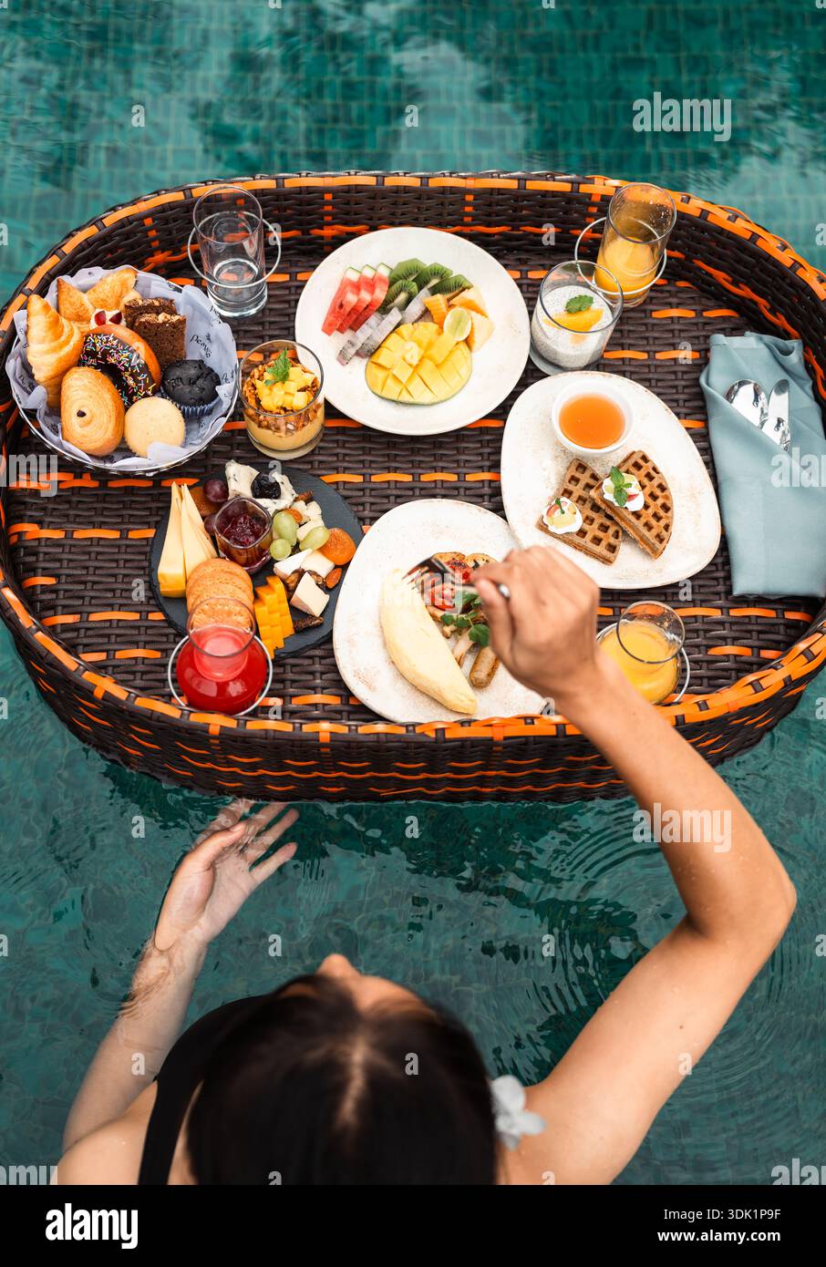 Vue aérienne d'une femme appréciant un petit déjeuner dans la piscine flottante Banque D'Images