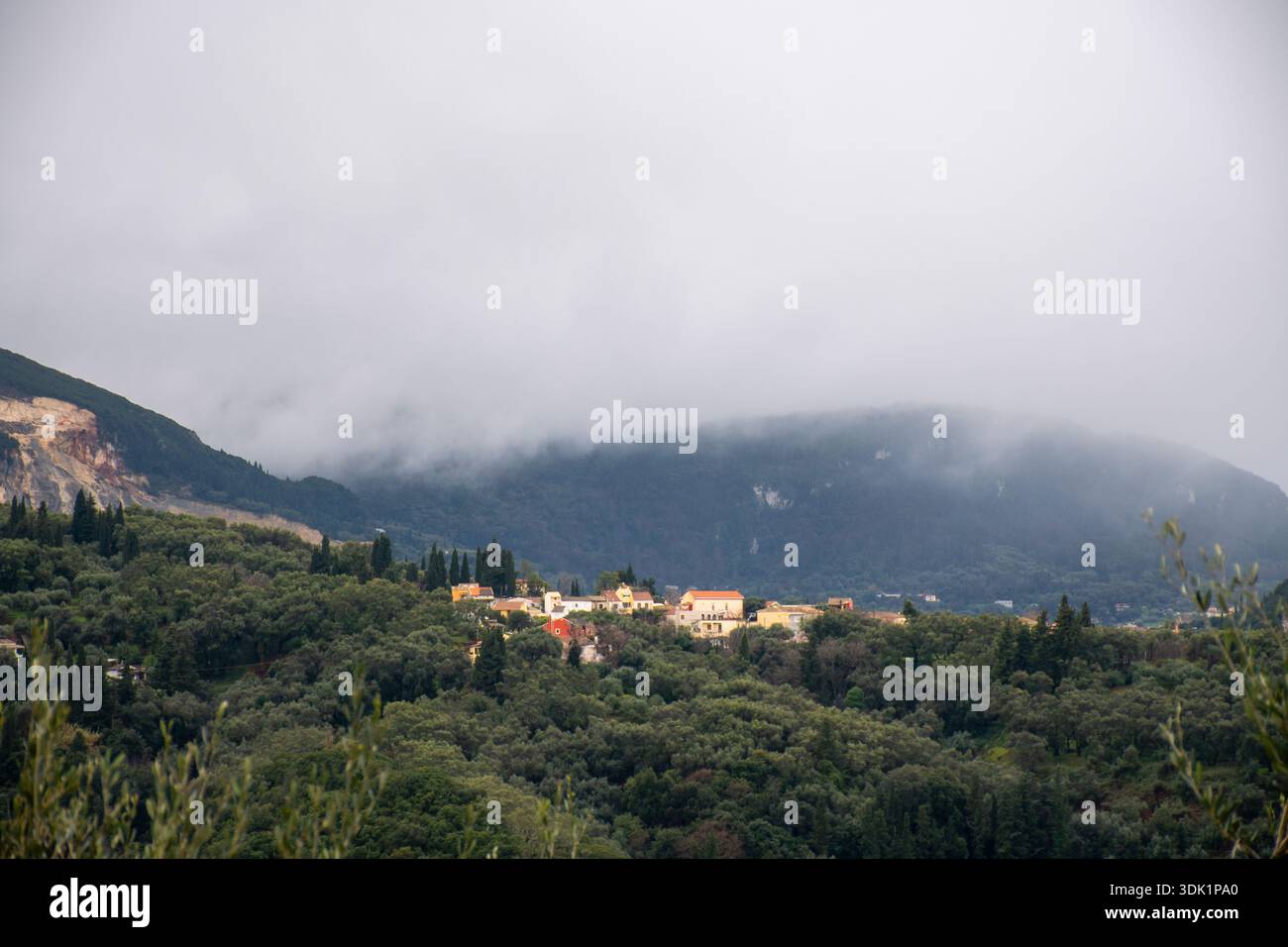 Plan de paysage grand angle du village de Valaneio à Corfou en Grèce montrant la végétation forestière dense et une carrière sur le flanc de la montagne sous une forte brume Banque D'Images