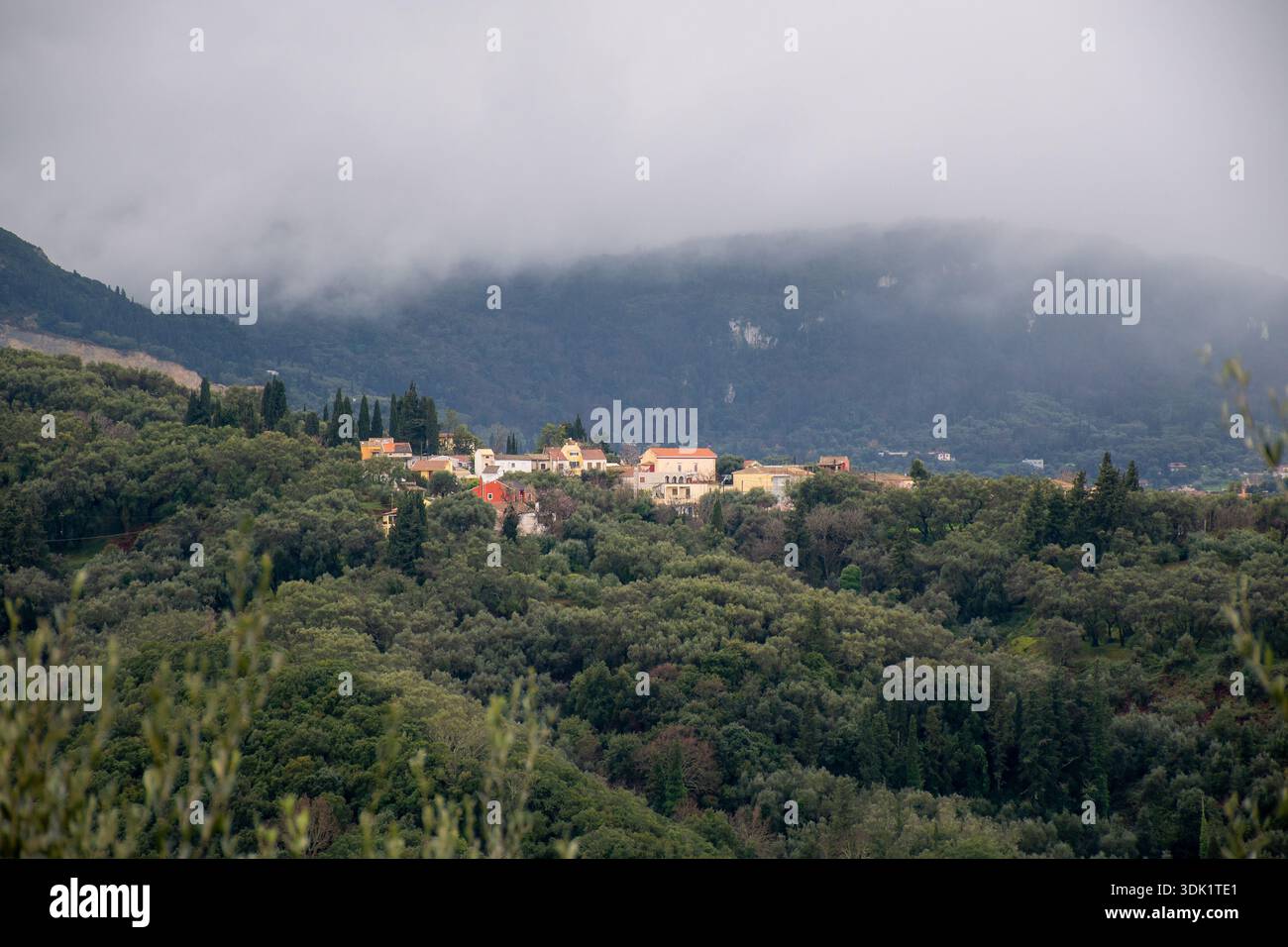 Paysage panoramique des collines verdoyantes de Corfou Grèce avec le village traditionnel de Valaneio sur fond de montagnes brumeuses et Banque D'Images
