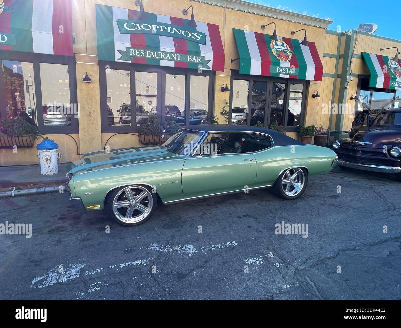 Voiture muscle américaine classique garée à l'extérieur du Cioppino's Restaurant & Bar, scène de rue ensoleillée. - Image de stock capturée avec un smartphone
