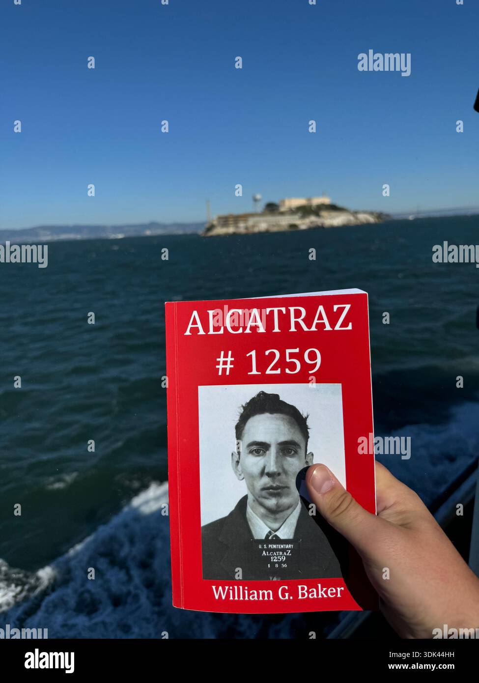 Touriste tenant la carte d'identité du détenu d'Alcatraz avec l'île de prison en arrière-plan à travers la baie de San Francisco. Banque D'Images