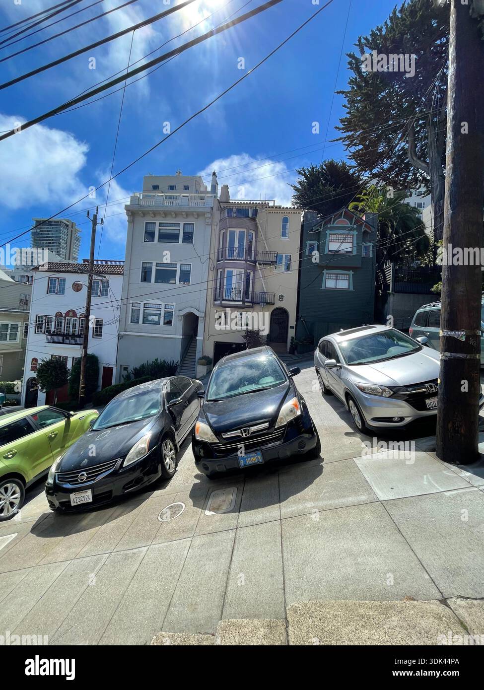 Rue escarpée avec des voitures garées et des maisons colorées sous le ciel bleu à San Francisco, Californie, États-Unis. - Image de stock capturée avec un smartphone