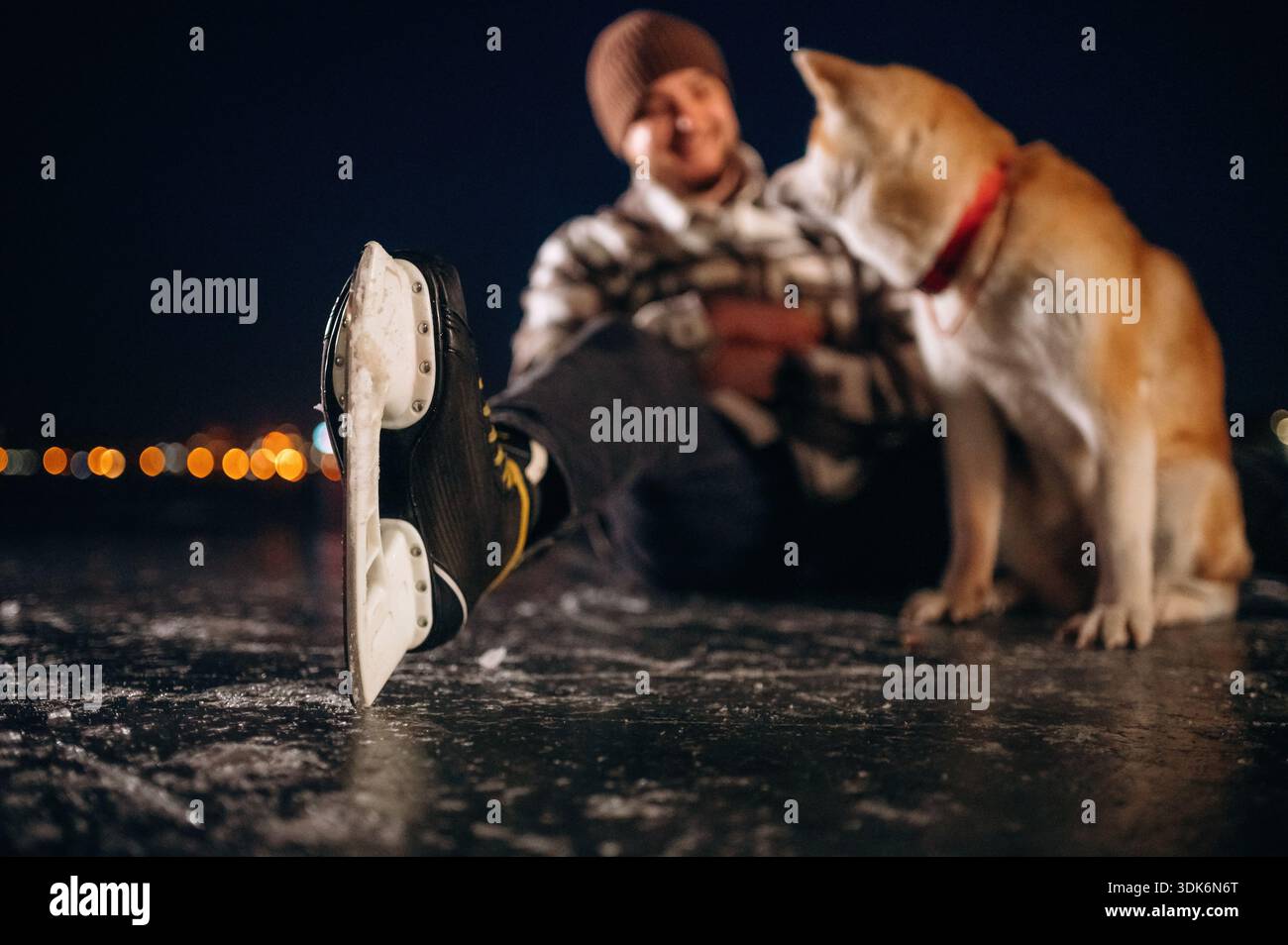 Beaux moments avec animal de compagnie mignon. Homme avec chien Akita Inu est sur la glace avec des patins en hiver. Banque D'Images