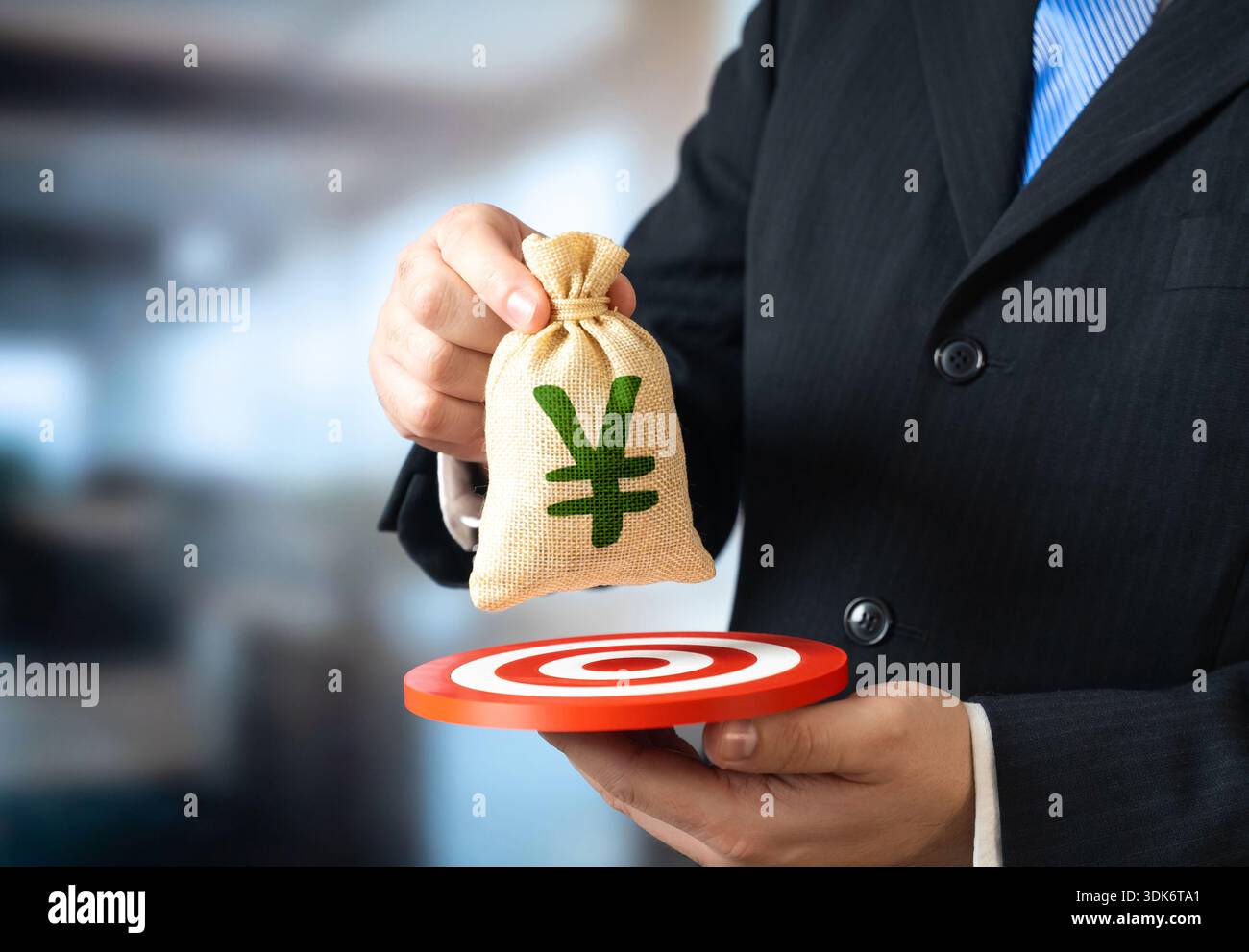 Un homme d'affaires tient un sac de yens ou de yuans et une cible. Atteindre le public cible pour un profit maximum. Dépôts et prêts. Inflation et taux d'intérêt. Banque D'Images