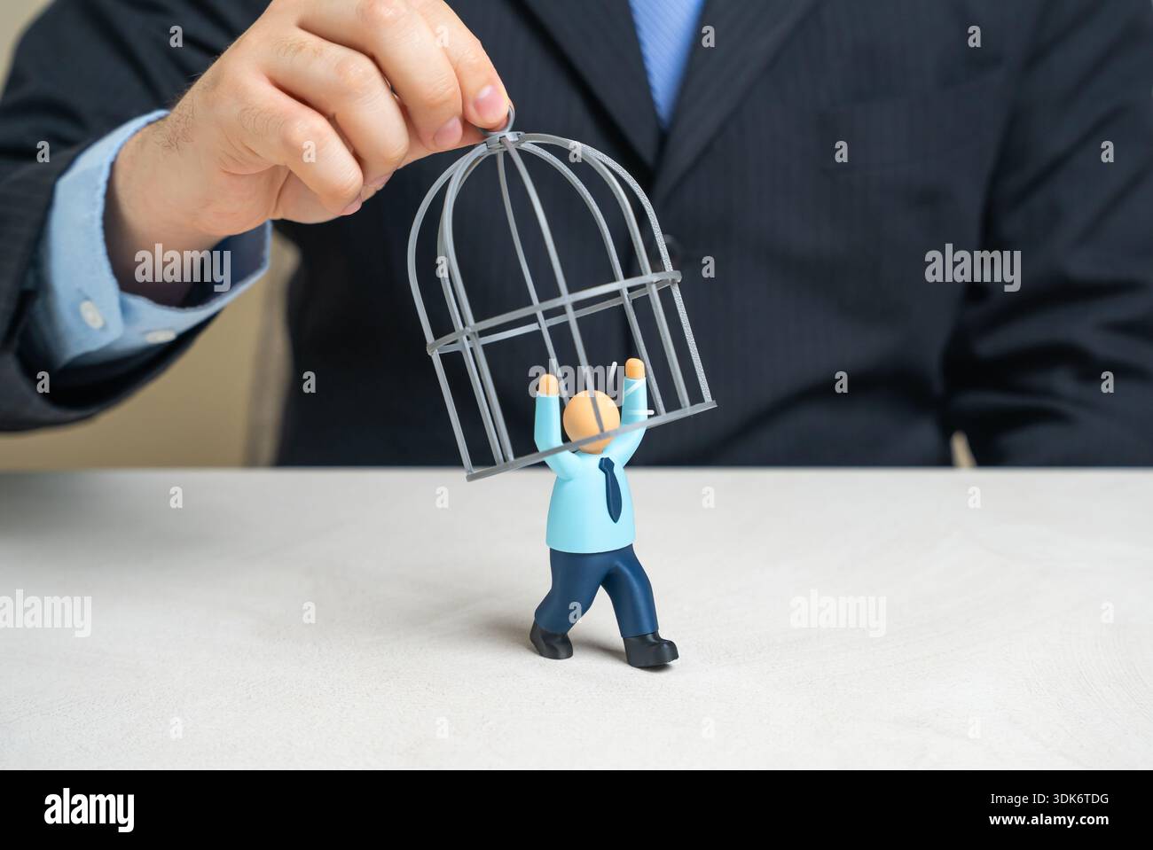 Un homme d'affaires essaie de mettre en cage un employé de bureau pour retenir des employés précieux. Pression de rétention des talents, métaphore du contrôle toxique et limite éthique Banque D'Images