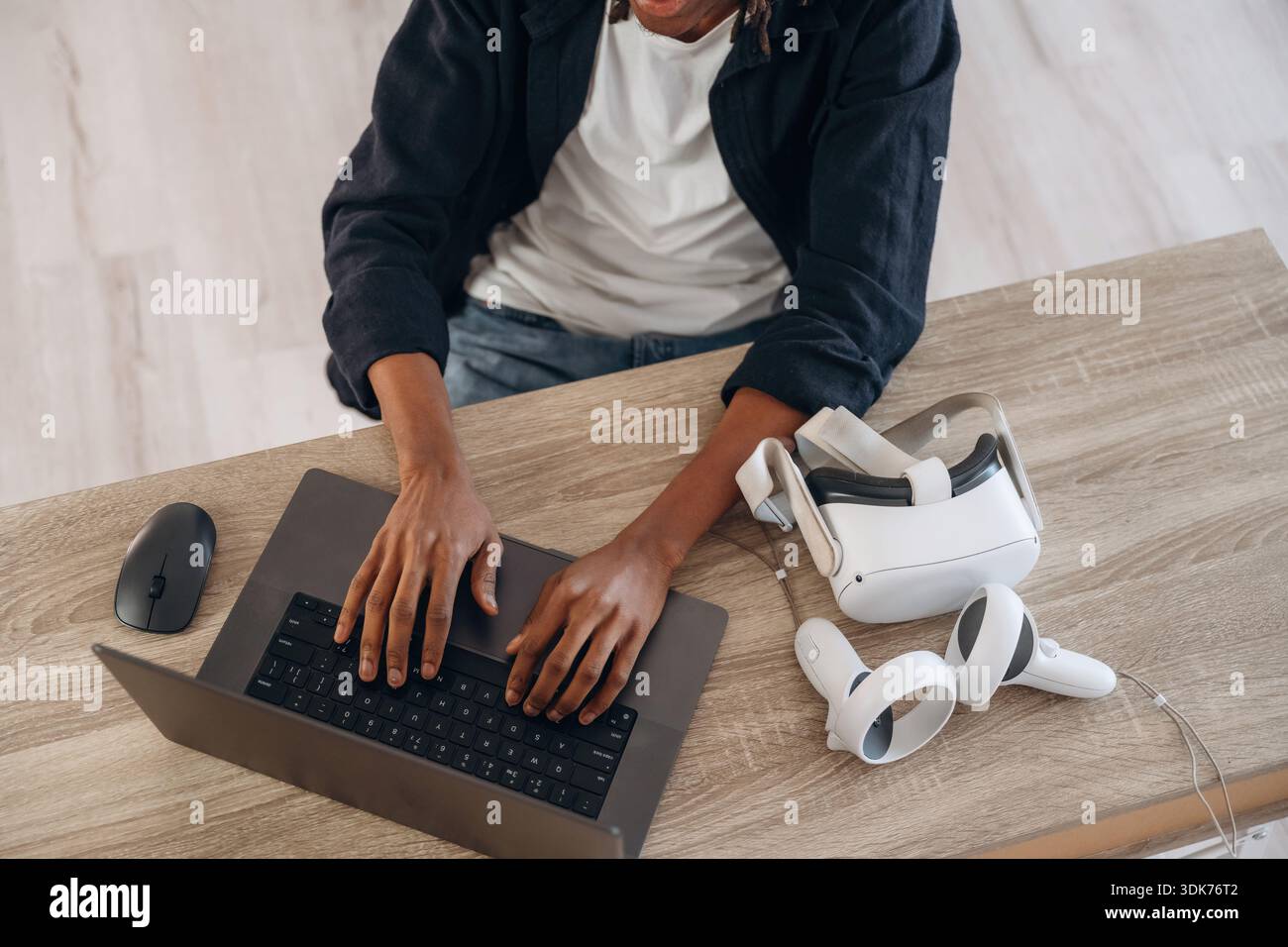 Le jeune homme est assis à table avec un ordinateur portable et des lunettes de réalité virtuelle. Banque D'Images