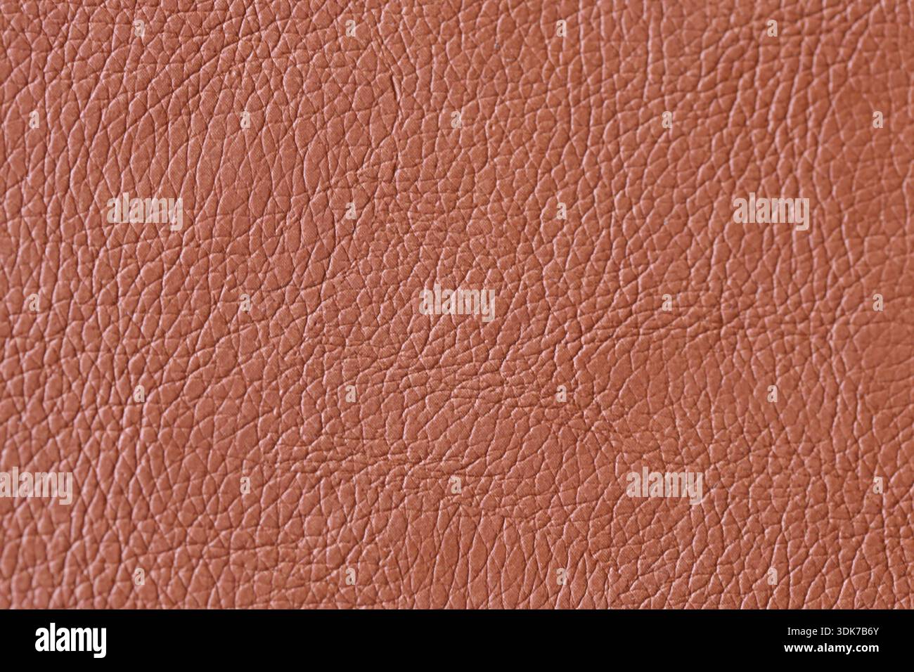 Texture plein cadre de faux cuir brun matériau : gros plan d'une surface synthétique grainée avec motif en cuir naturel et tons terreux chauds Banque D'Images
