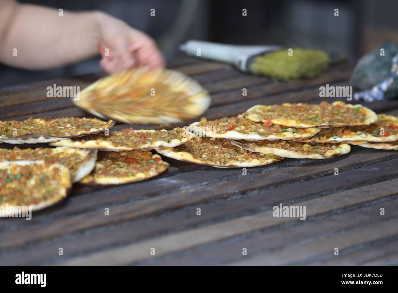 Lahmacun turc fraîchement cuit dans une boulangerie traditionnelle : pain plat mince et croustillant au four de pierre garni de viande hachée, de légumes et d'herbes sur un Woode Banque D'Images