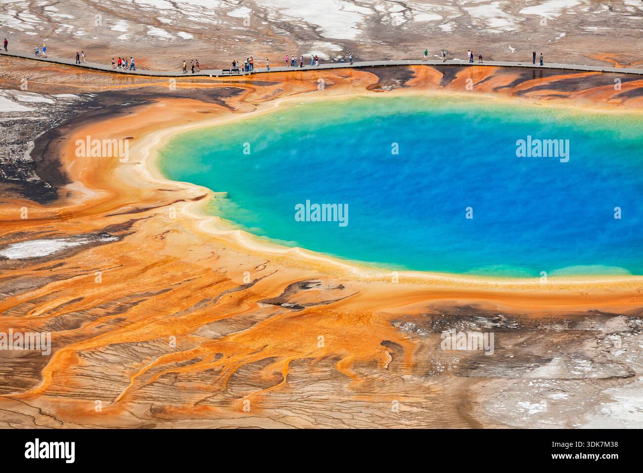 Grande source prismatique colorée dans le Midway Geyser Basin de Yellowstone avec des teintes arc-en-ciel vives et des touristes sur la promenade. Banque D'Images