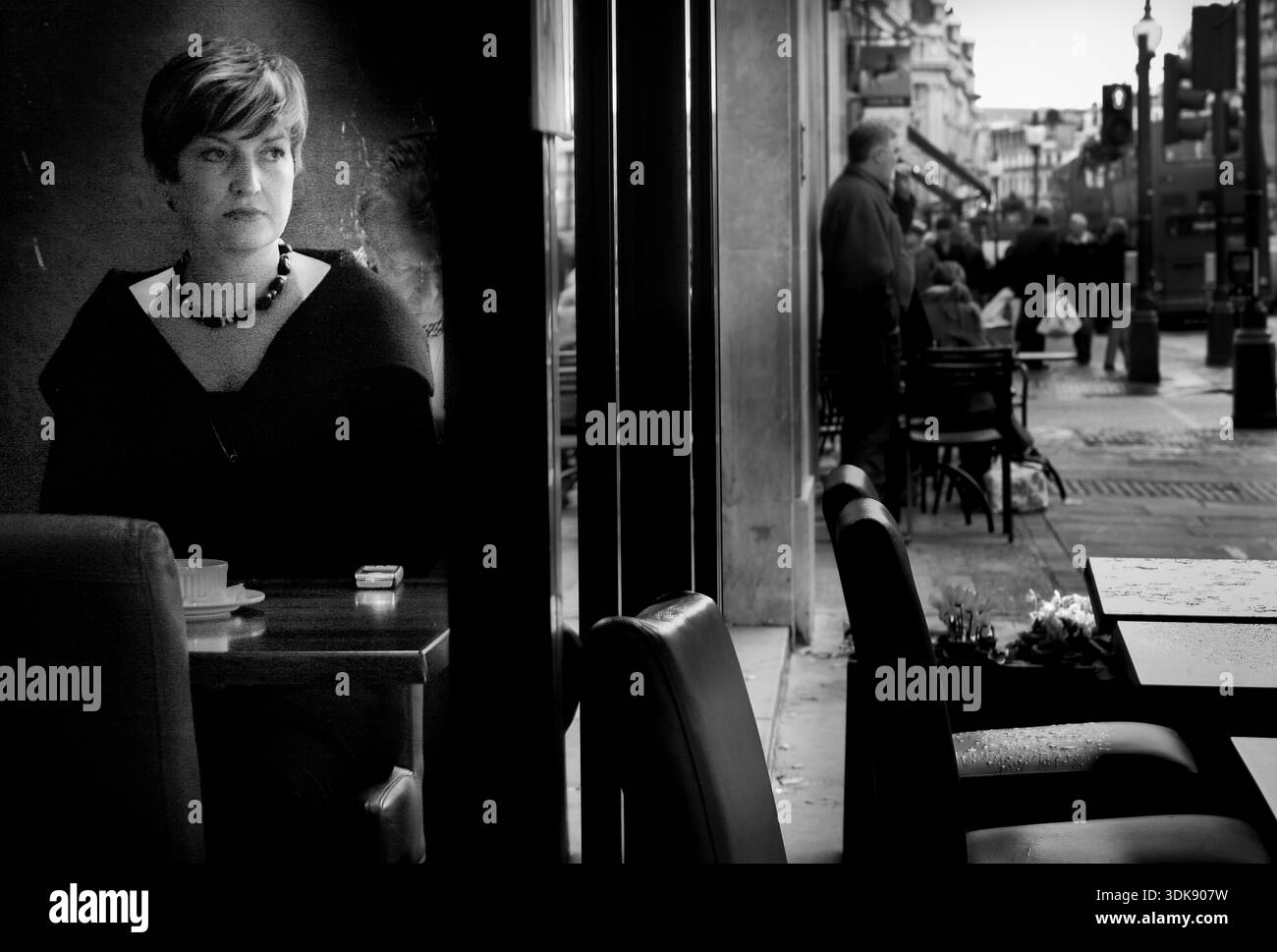 Femme dans un café regardant à travers la fenêtre, scène de rue, Londres, image N/B. Banque D'Images