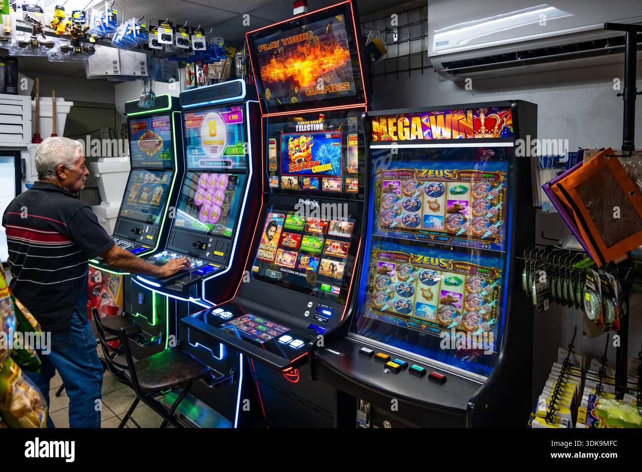 Un vieil homme jouant à la machine à sous dans une station-service. Porto Rico. Banque D'Images