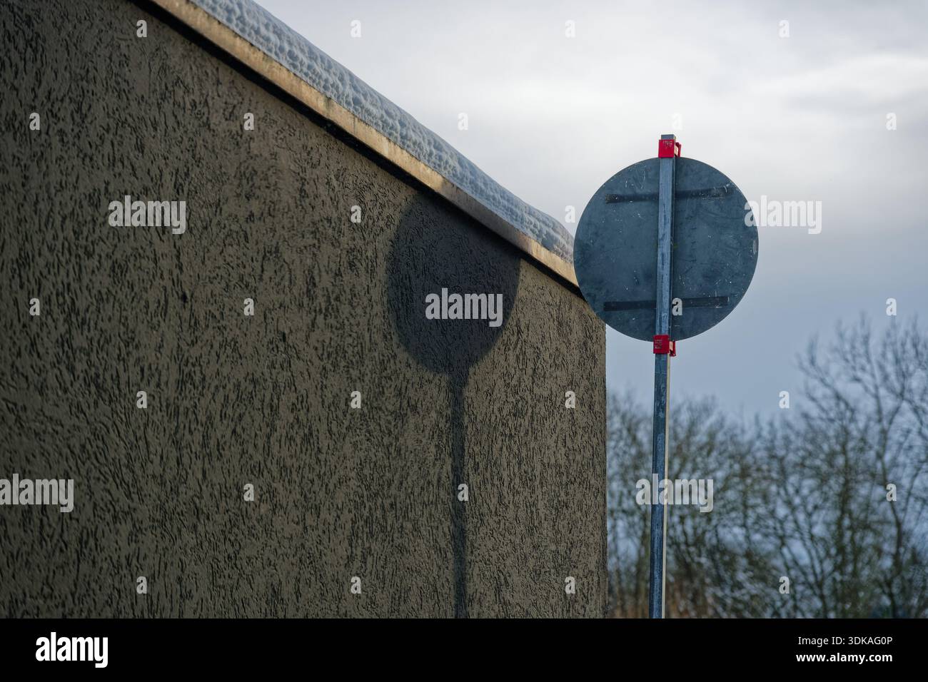 Composition minimaliste montrant une ombre sombre d'un signe circulaire contre un mur gris sous la lumière du soleil. Idéal pour les arrière-plans artistiques et la métaphore Banque D'Images