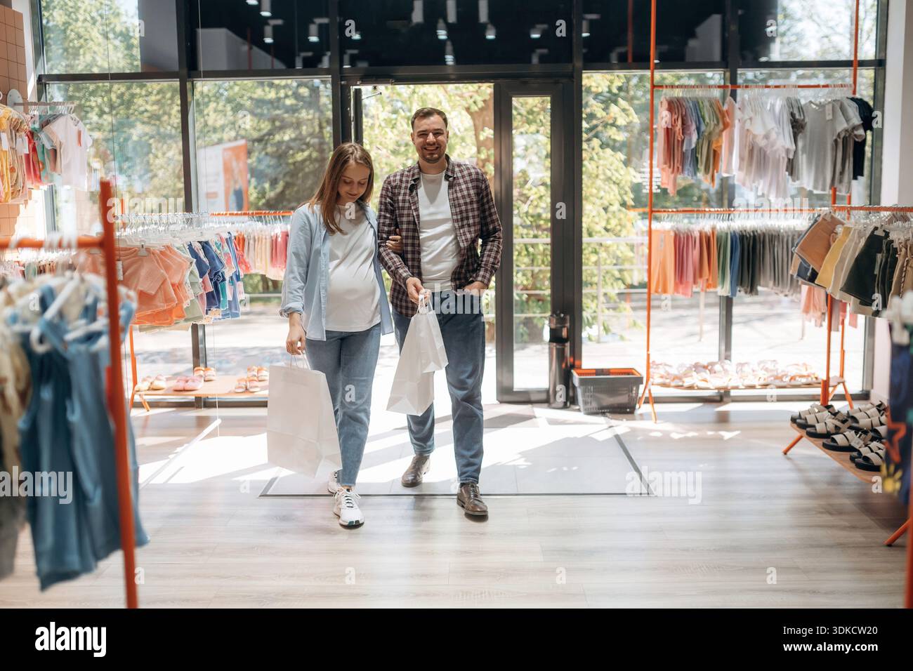 Expressions faciales positives. Femme enceinte avec homme sont dans le magasin de vêtements pour enfants. Banque D'Images