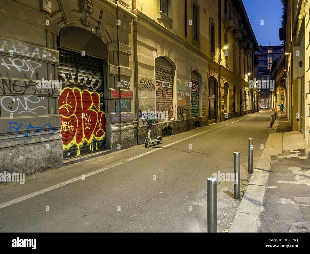 Mur couvert de graffitis le long d'une rue calme au crépuscule à Milan, Lombardie, Italie. Banque D'Images