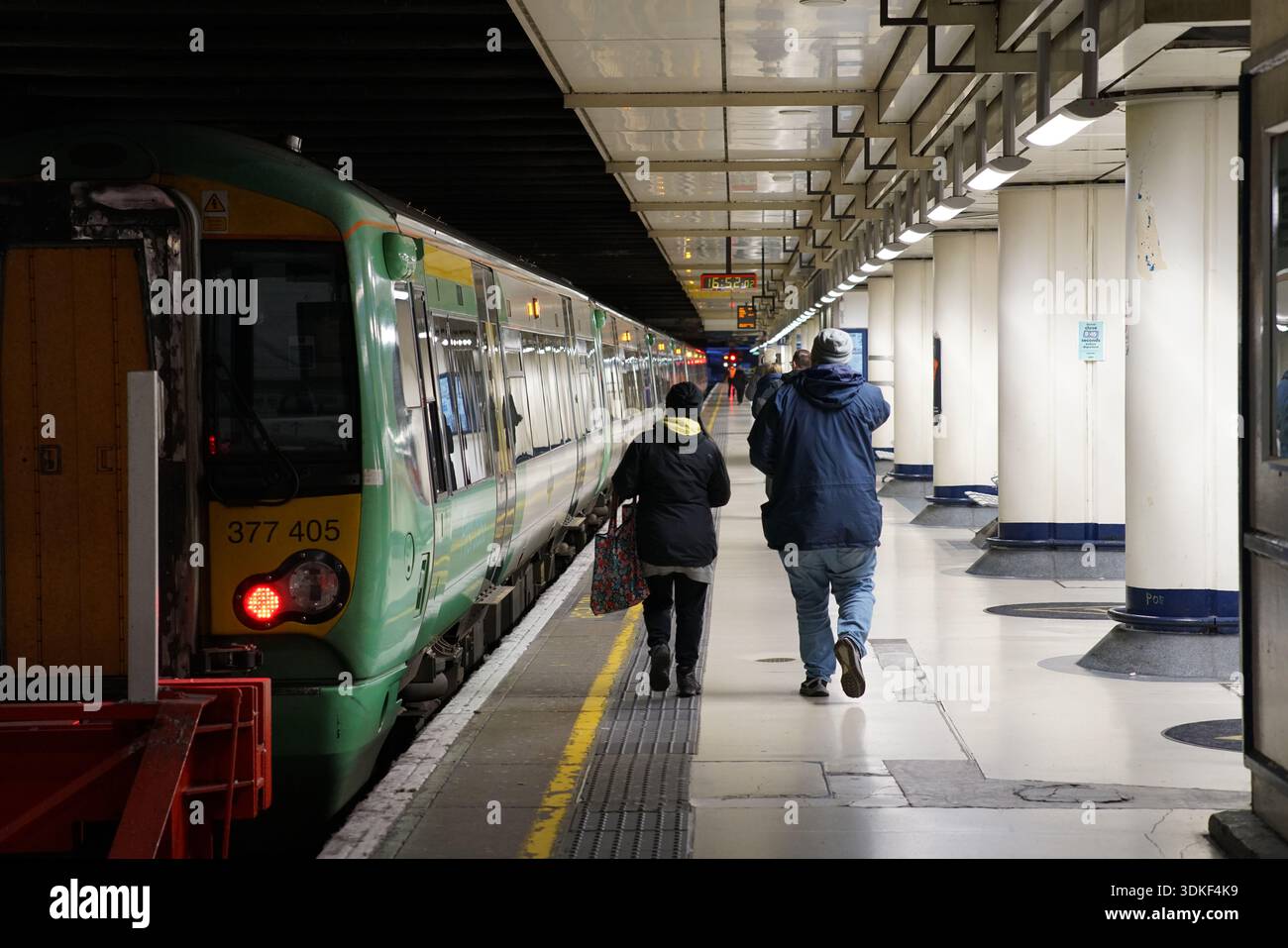Les navetteurs marchant le long de la plate-forme devant un train vert Southern Class 377 à la gare Victoria de Londres, Londres, Angleterre Banque D'Images