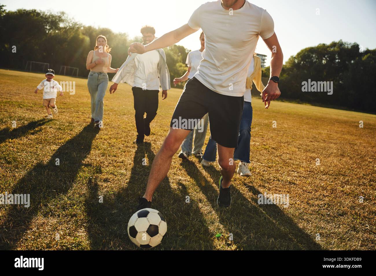 Courir ensemble. Groupe d'amis jouent au football sur le terrain. Banque D'Images
