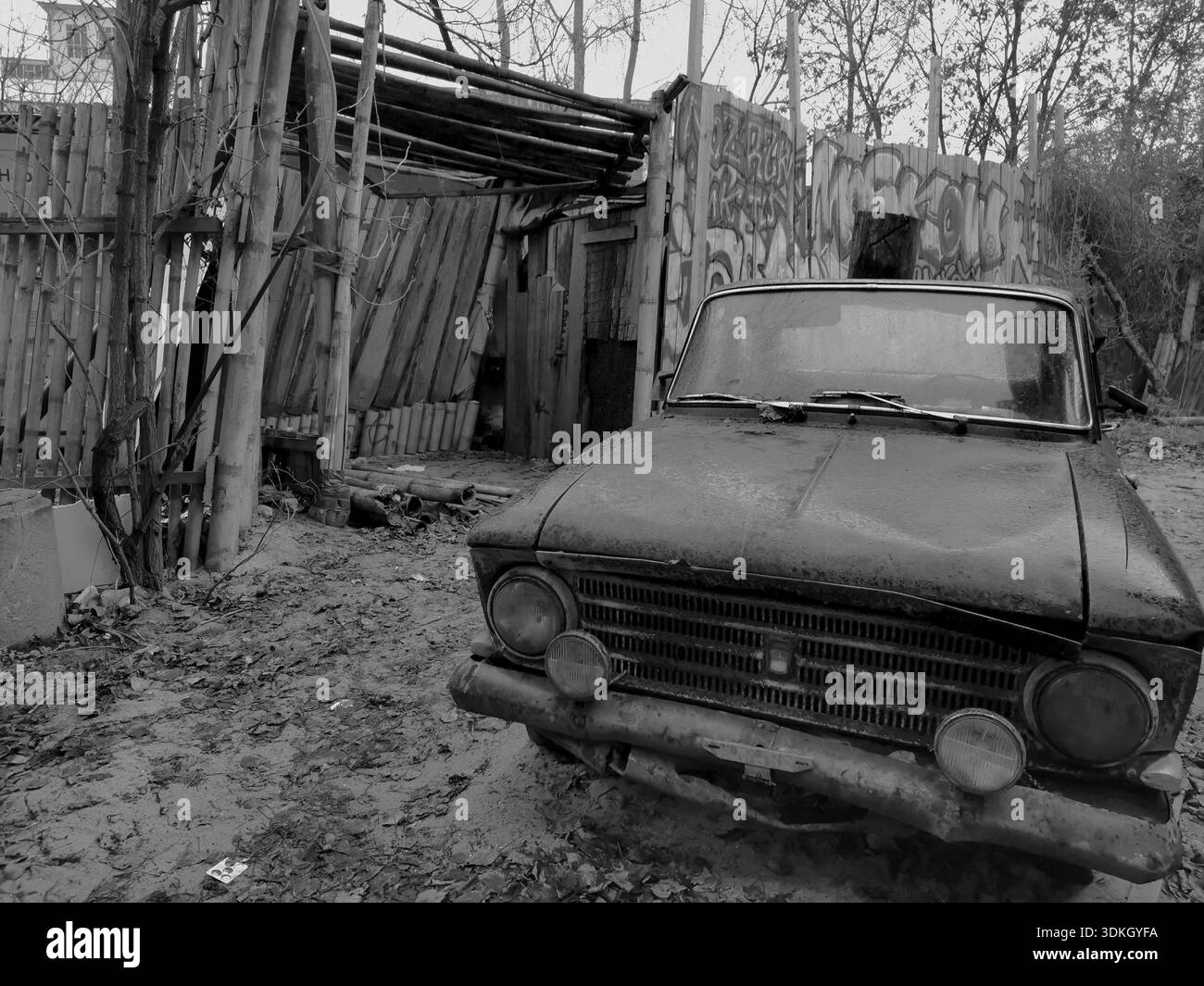 Vieille voiture abandonnée devant un bâtiment délabré avec des graffitis, Berlin, Allemagne Banque D'Images