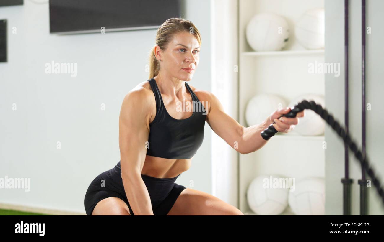 Entraînement de femme athlétique avec des cordes de combat dans le gymnase Banque D'Images