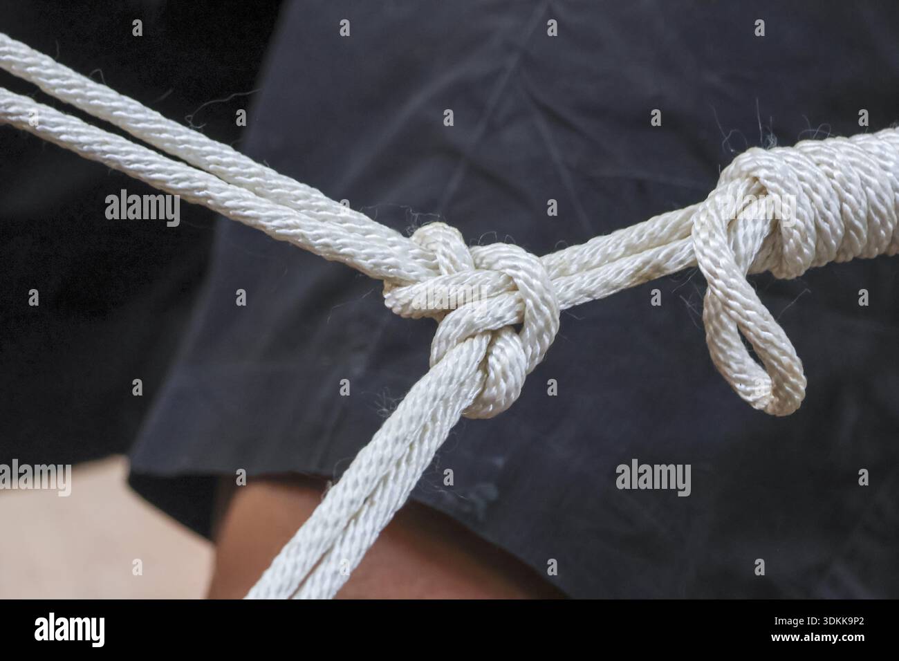 Attachez le nœud de corde blanche pour la connexion et le travail d'équipe. cordon torsadé résistant pour une solidité, une fixation et une liaison sécurisée dans les détails macro rapprochés Banque D'Images