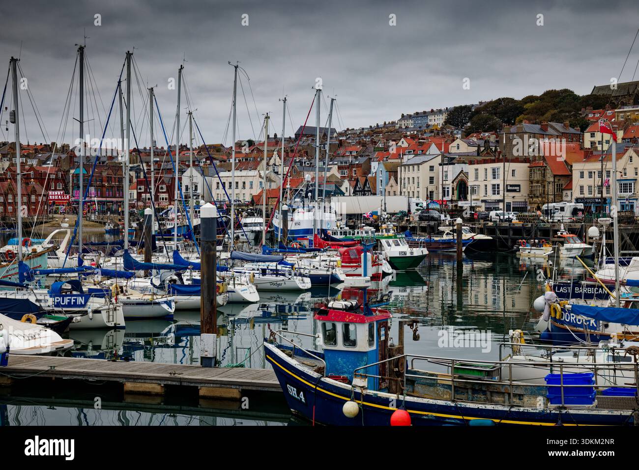 Un port animé plein de yachts amarrés avec le front de mer de la ville et le port en arrière-plan, Scarborough, North Yorkshire. Banque D'Images