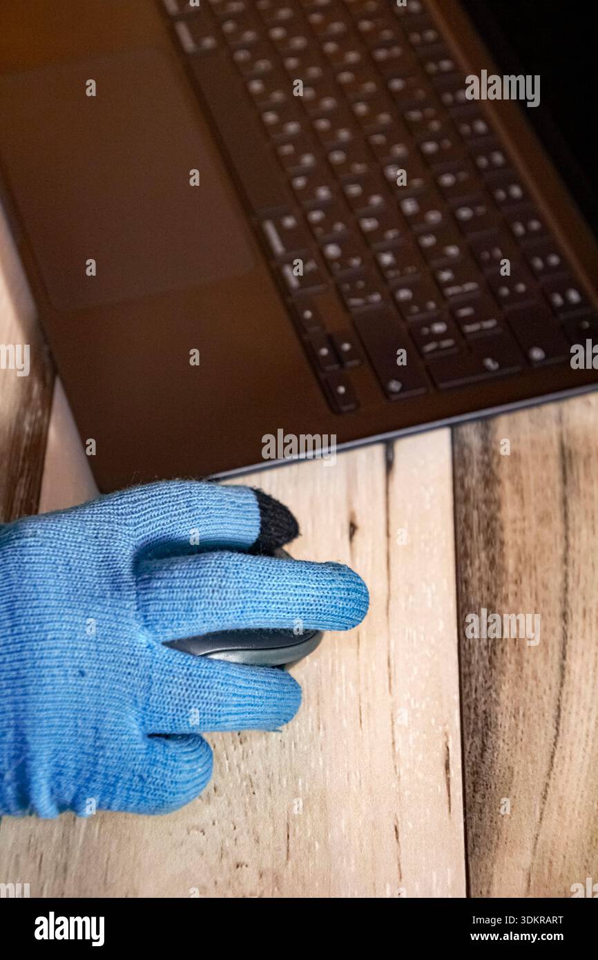 Gros plan vertical d'une main dans un gant bleu sur une souris d'ordinateur pendant la panne d'hiver, le travail à domicile et la vie freelance dans des conditions froides. Banque D'Images