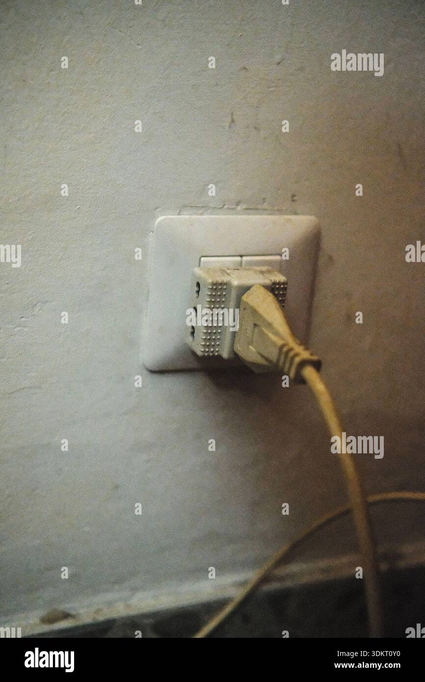 Prise électrique sur un vieux mur blanc Banque D'Images