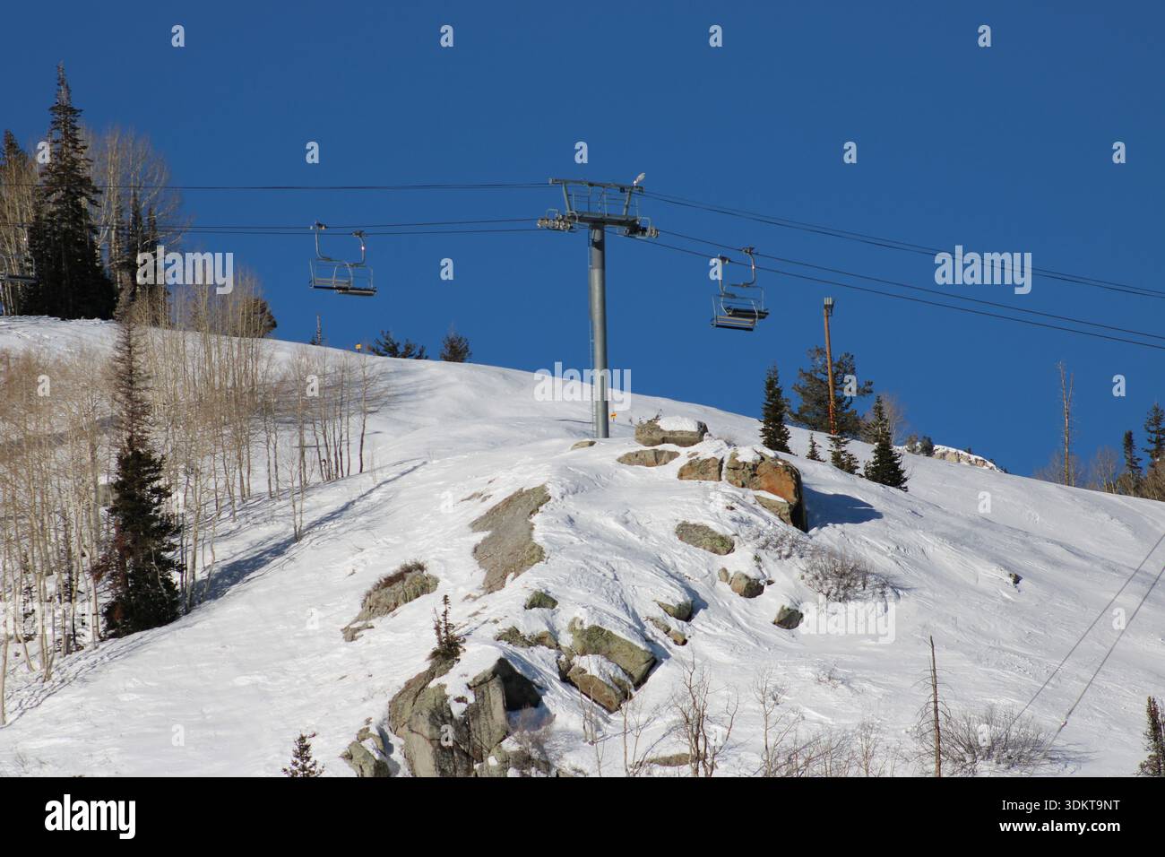 Remontée mécanique vide traversant une colline alpine enneigée Banque D'Images
