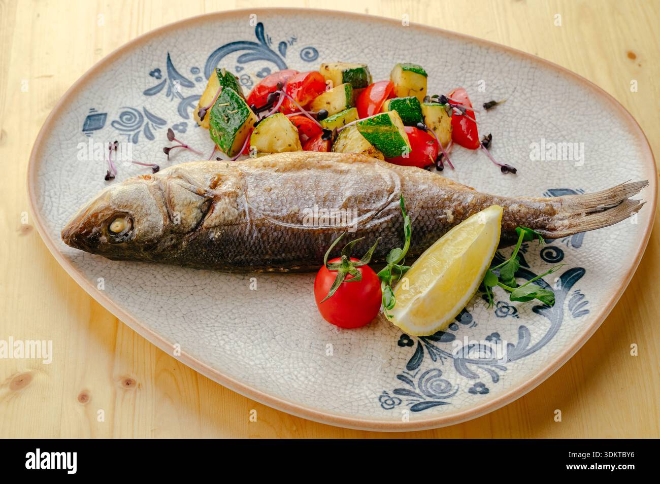 bar frit sur une assiette avec des légumes Banque D'Images