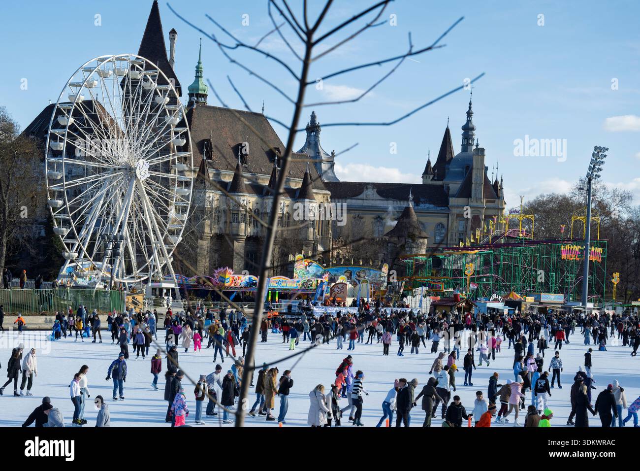 Budapest, Hongrie, grande foule de gens qui aiment le patinage sur glace et les sports d'hiver sur une patinoire extérieure pendant une journée ensoleillée. Avec un parc d'attractions featurin Banque D'Images