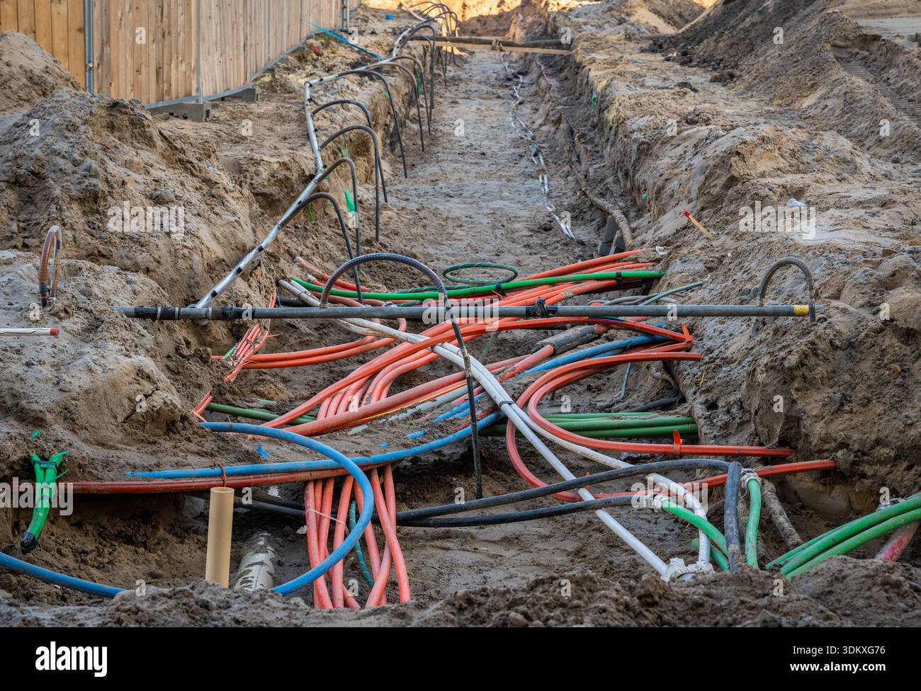 Câbles de service souterrains sur le chantier de construction, plusieurs lignes électriques et de communication posées dans le sol prêt pour le remblayage Banque D'Images