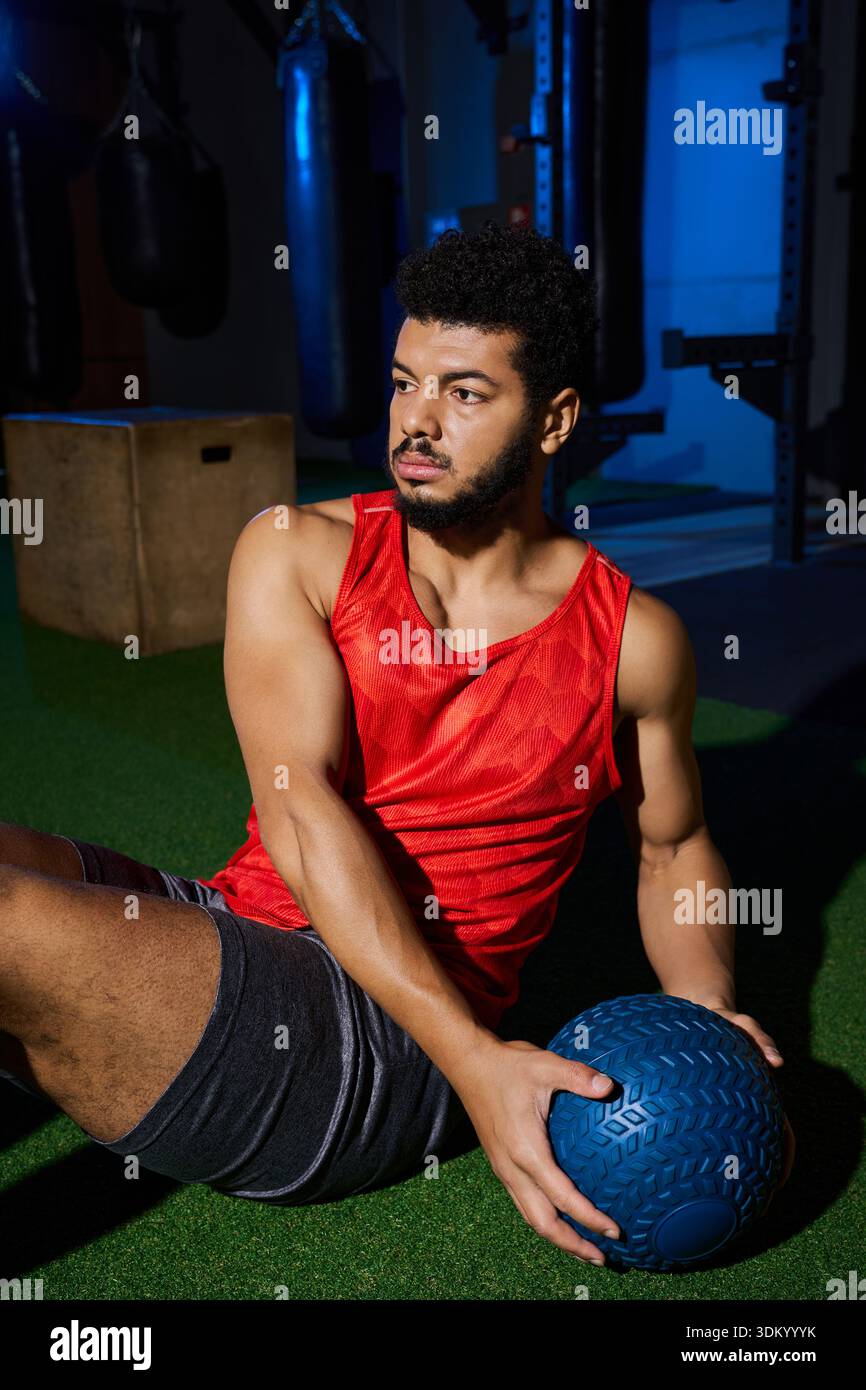 Un jeune homme afro-américain exerce avec concentration, en utilisant un medecine ball à l'intérieur. Banque D'Images
