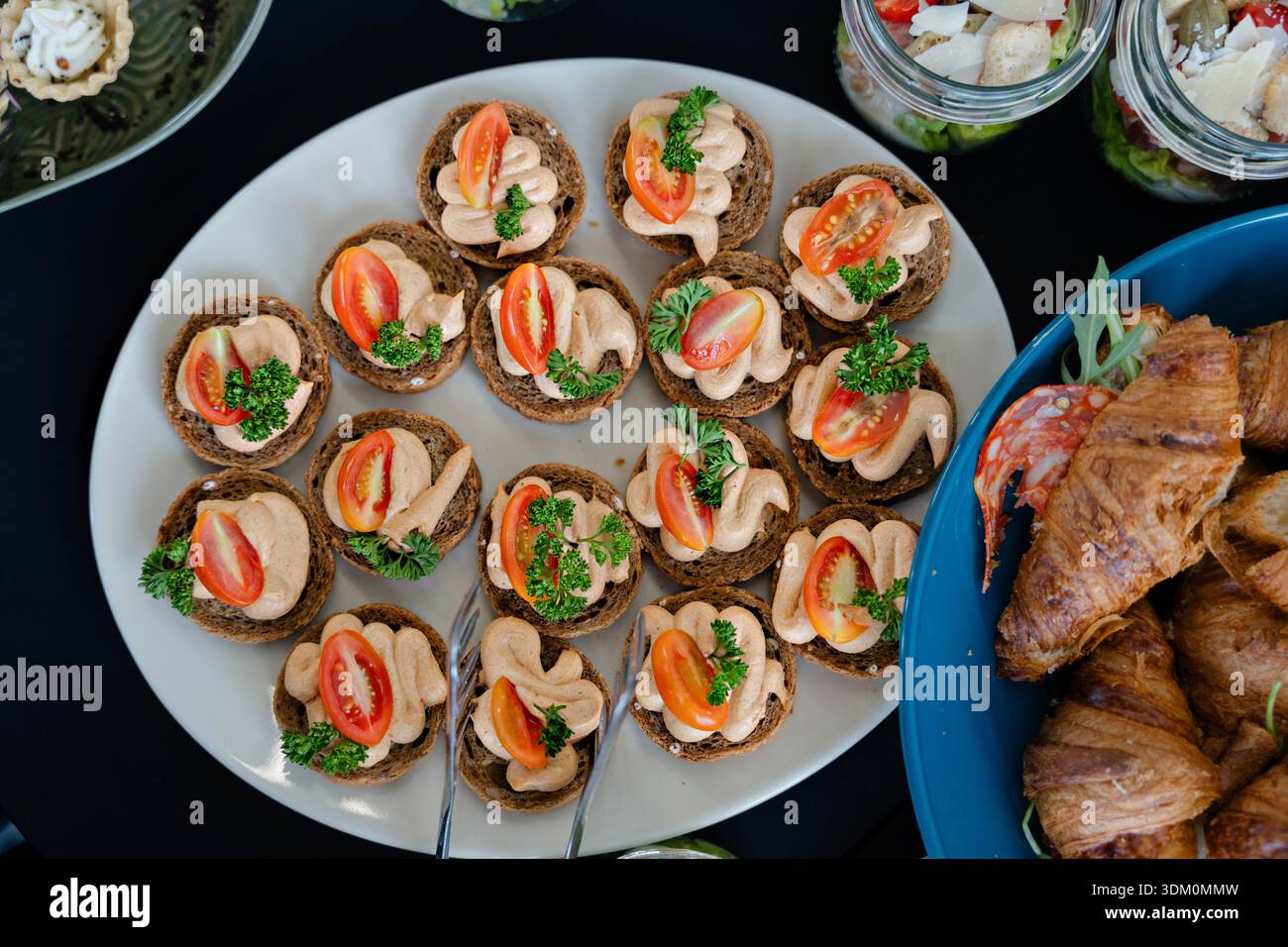 Canapés savoureux élégants avec mousse crémeuse, tomates cerises et herbes fraîches disposés sur l'assiette pour un buffet traiteur ou un brunch Banque D'Images