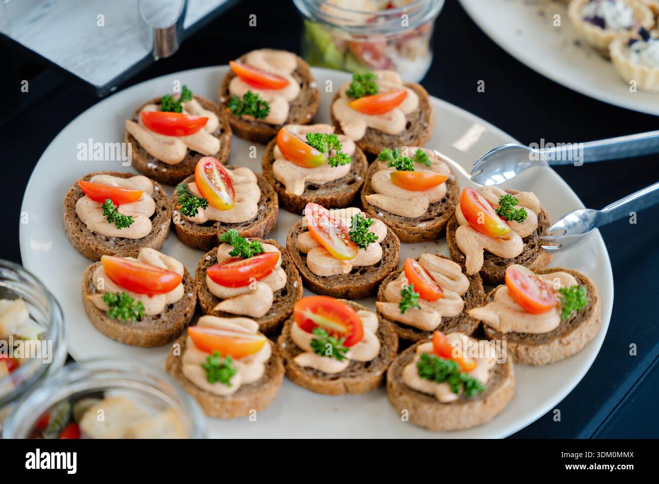 Canapés savoureux élégants avec mousse crémeuse, tomates cerises et herbes fraîches disposés sur l'assiette pour un buffet traiteur ou un brunch Banque D'Images